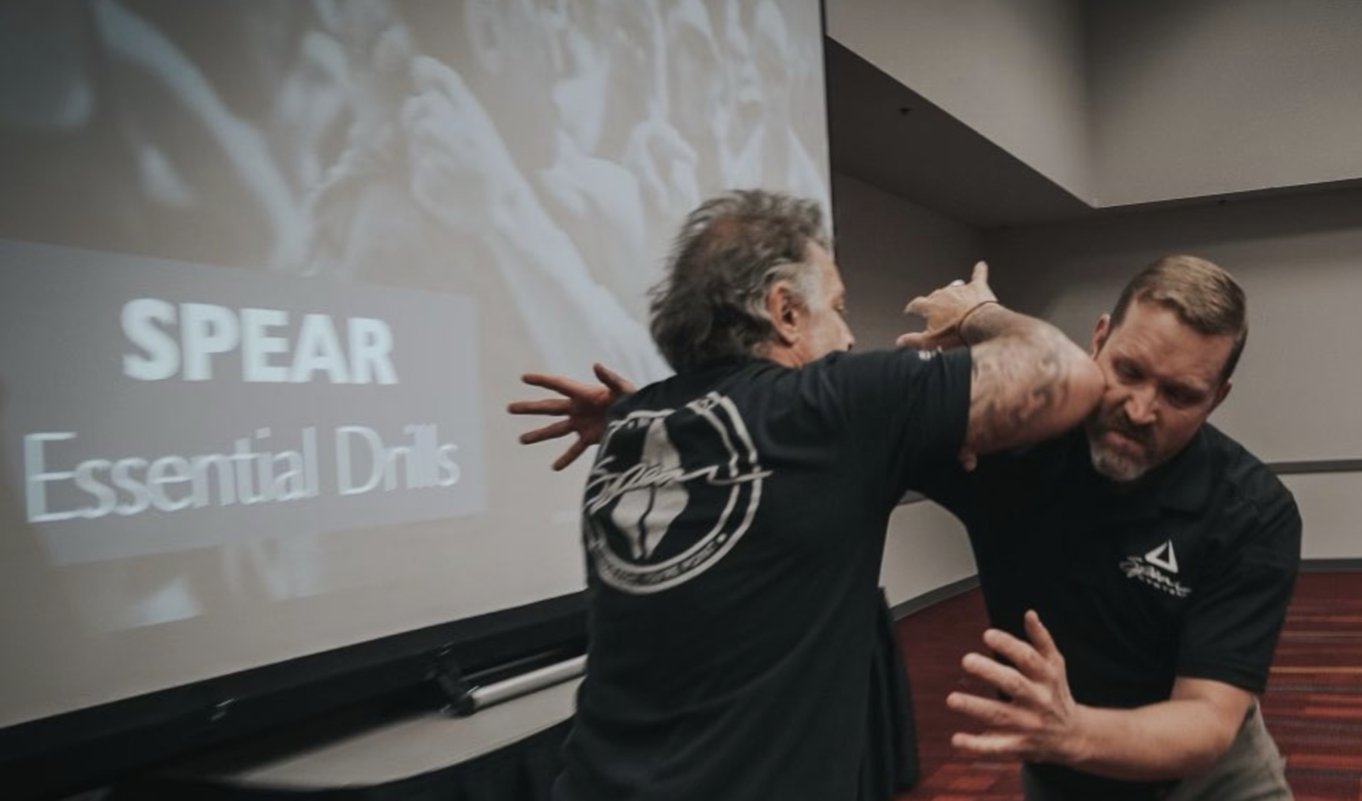 Coach Blauer demonstrating a SPEAR System drill on stage during an Essential Drills session